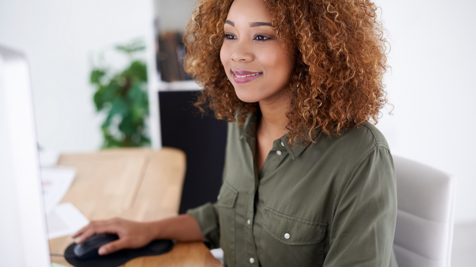 A woman sitting at a desk, sending emails on her computer