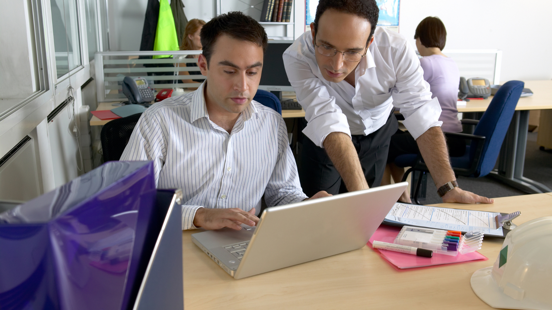 Two men working in a construction office looking at a laptop