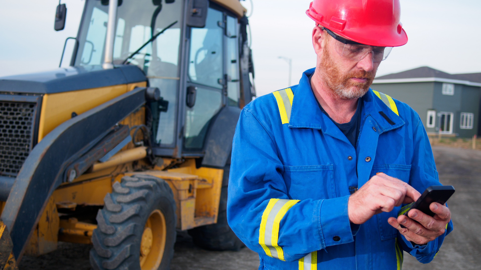 Man in a hard hat at a construction site working from his phone