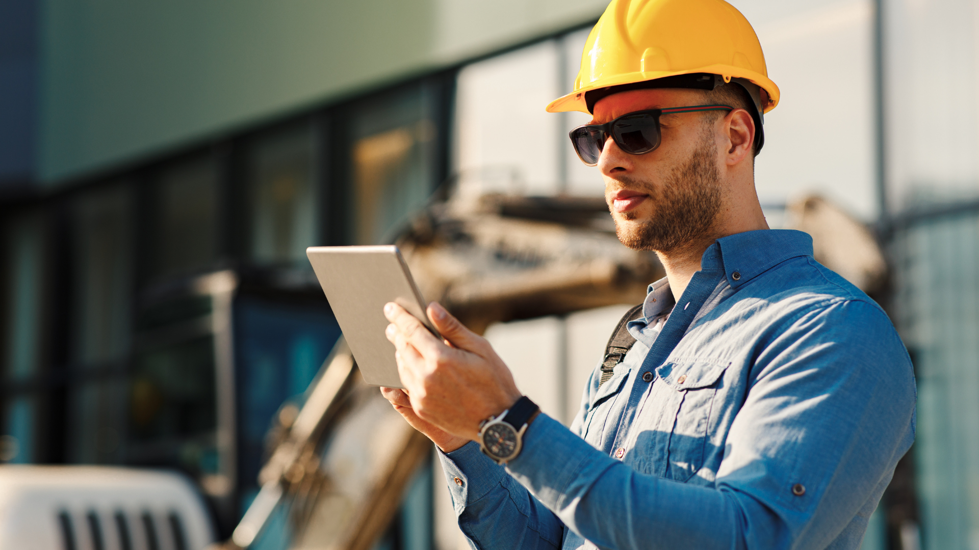 Construction worker on site in a hard hat, working from a tablet