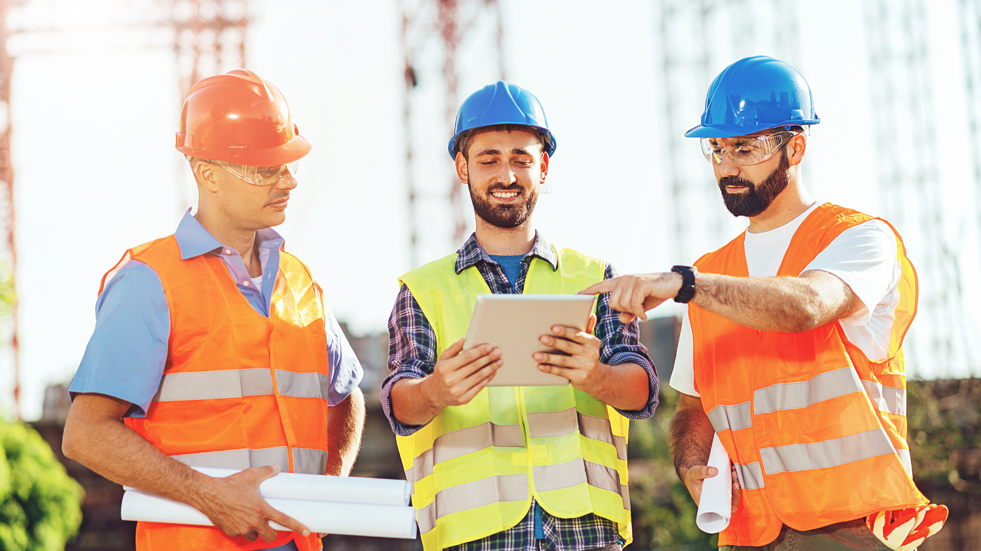 Three construction workers on site reviewing information on a tablet