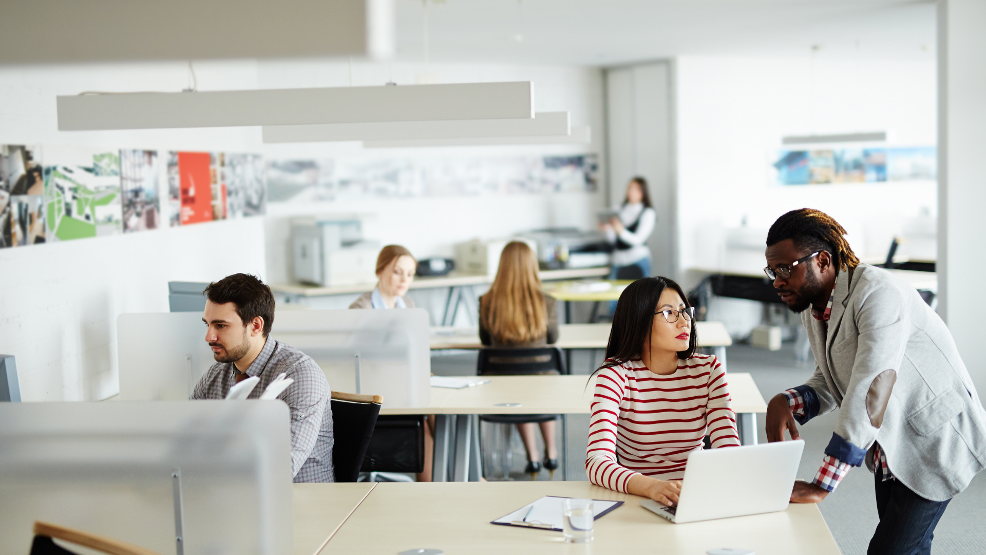 Office space with colleagues working on computers and tablets