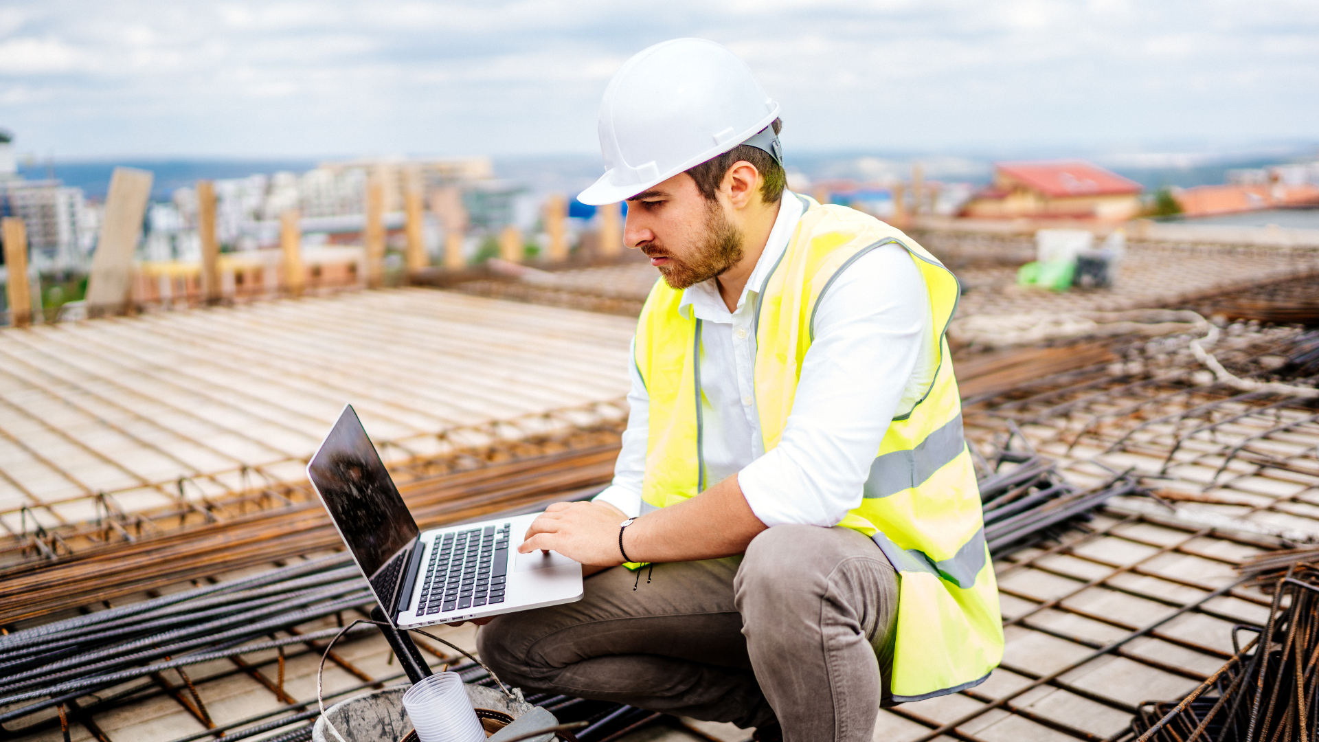 Construction worker on a roof working with his laptop