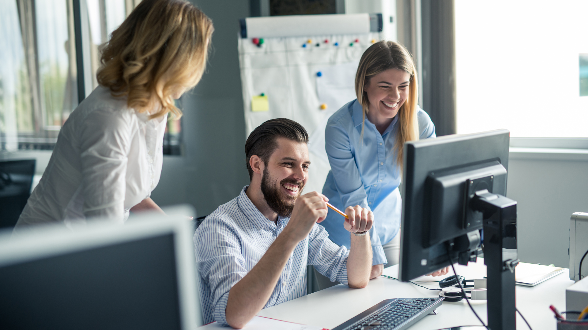 Three coworkers in an office viewing a computer screen