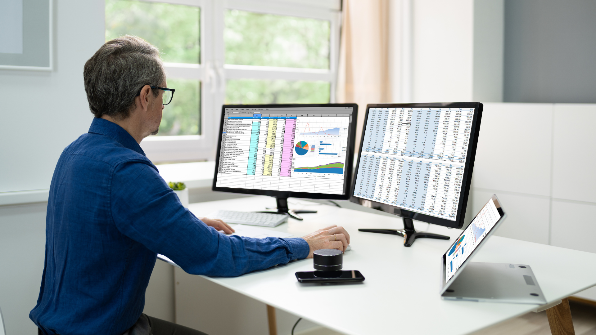 A man working at a des with two computer monitors up showing data from software system