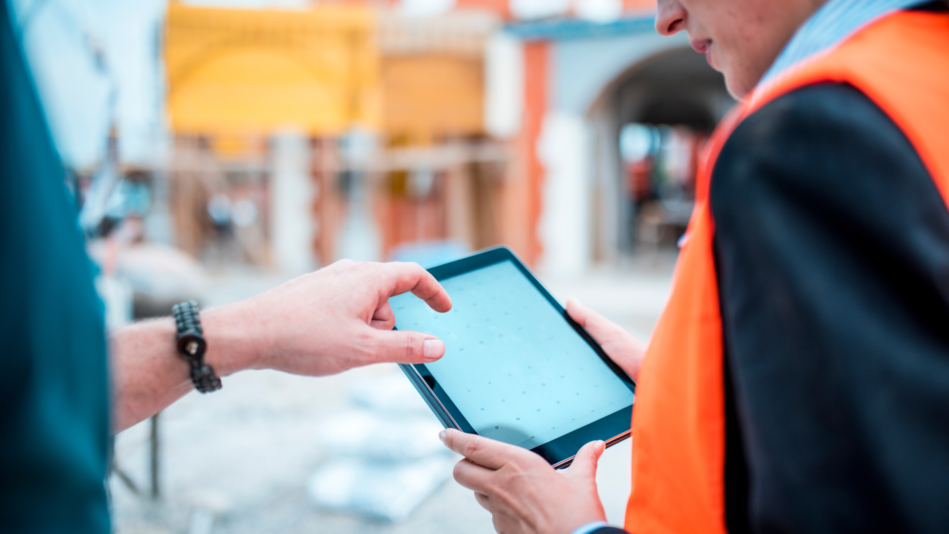 Construction workers on site looking at a calendar view on a tablet